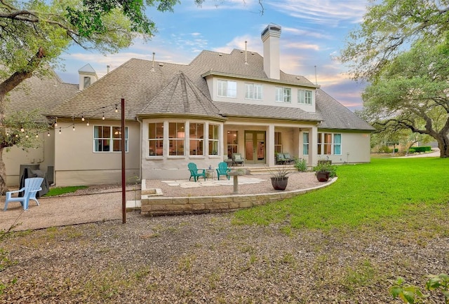 9301 San Lucas Dr, Austin, TX 78737 - rear view of house with a patio area, a chimney, a lawn, stucco siding, and roof with shingles