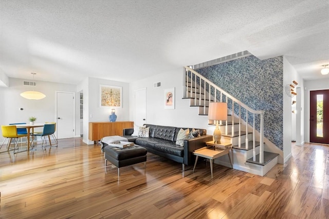 3104 Rexford Dr, Austin, TX 78723 - living room with wallpapered walls, a textured ceiling, stairway, wood finished floors, and an accent wall