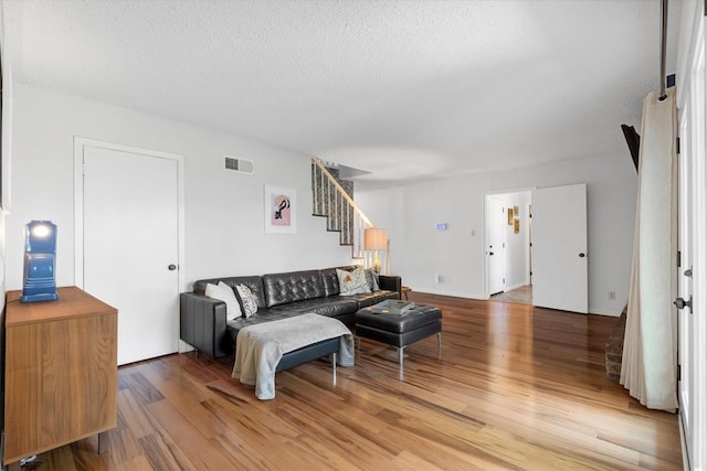 3104 Rexford Dr, Austin, TX 78723 - living room with stairs, light wood-style flooring, and a textured ceiling