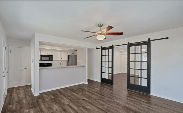 1709 Greenlawn Blvd, Round Rock, TX 78664 - unfurnished living room featuring a barn door, dark wood-type flooring, and ceiling fan