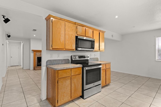 3809 Joshua Taylor Dr, Killeen, TX 76549 - kitchen featuring stainless steel appliances, light tile patterned flooring, recessed lighting, baseboards, and a brick fireplace