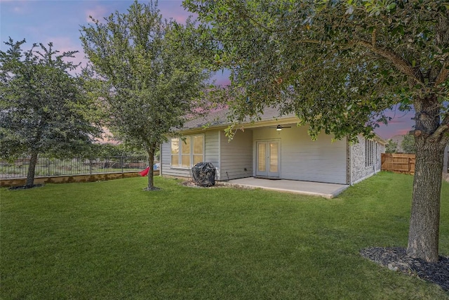 267 Razzmatazz Trl, Buda, TX 78610 - yard at dusk featuring a patio area, french doors, and a ceiling fan