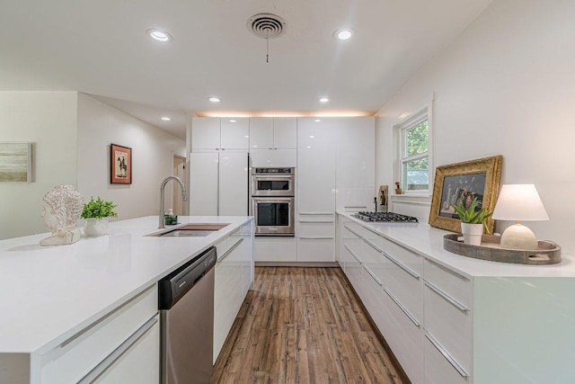 4714 Philco Dr, Austin, TX 78745 - kitchen featuring appliances with stainless steel finishes, a sink, modern cabinets, wood finished floors, and white cabinetry