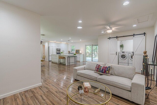 4714 Philco Dr, Austin, TX 78745 - living area with a barn door, washing machine and clothes dryer, light wood-style flooring, recessed lighting, and a ceiling fan