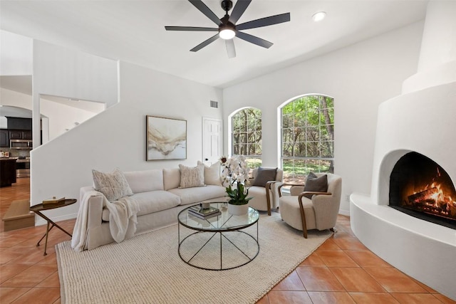 8311 Sumner Ct, Austin, TX 78733 - living room featuring a ceiling fan, light tile patterned floors, a warm lit fireplace, and recessed lighting