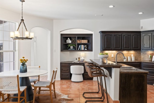 8311 Sumner Ct, Austin, TX 78733 - kitchen with light tile patterned floors, a chandelier, backsplash, a kitchen bar, and recessed lighting