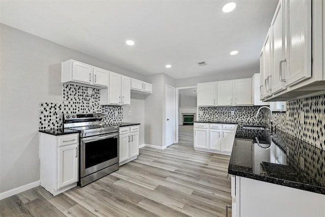707 Shamrock Dr, Leander, TX 78641 - kitchen with stainless steel range with electric cooktop, a sink, baseboards, backsplash, and white cabinets