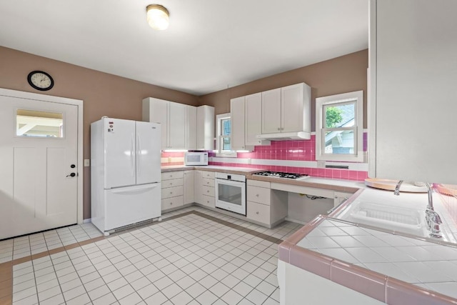 4314 Duval St, Austin, TX 78751 - kitchen featuring white appliances, tile countertops, white cabinets, decorative backsplash, and under cabinet range hood