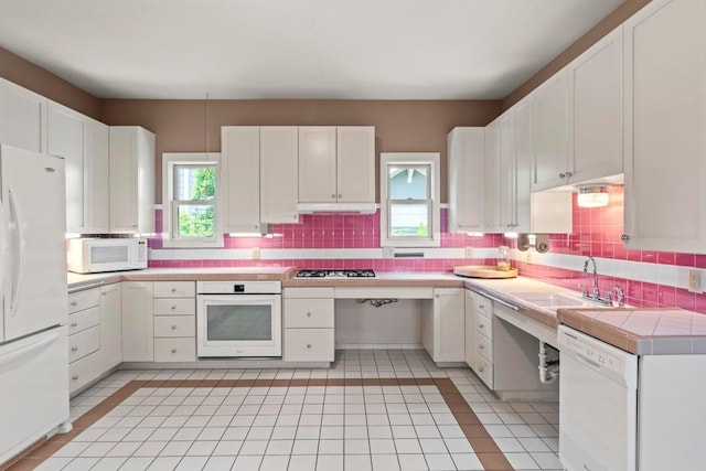 4314 Duval St, Austin, TX 78751 - kitchen with white appliances, a sink, backsplash, under cabinet range hood, and white cabinets