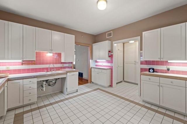 4314 Duval St, Austin, TX 78751 - kitchen with white dishwasher, white cabinets, tasteful backsplash, and tile counters