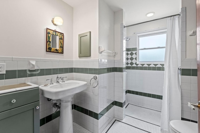 4314 Duval St, Austin, TX 78751 - full bathroom with toilet, a tile shower, a wainscoted wall, tile walls, and tile patterned flooring