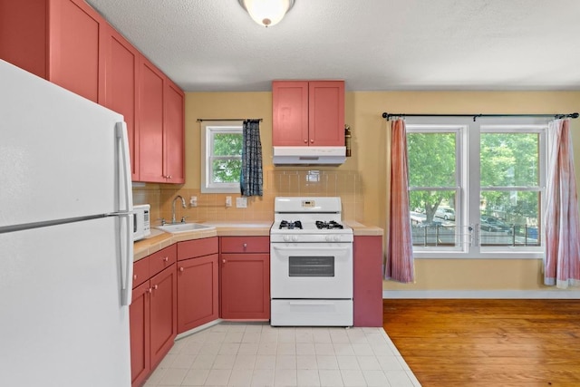 4314 Duval St, Austin, TX 78751 - kitchen with white appliances, under cabinet range hood, a sink, decorative backsplash, and baseboards