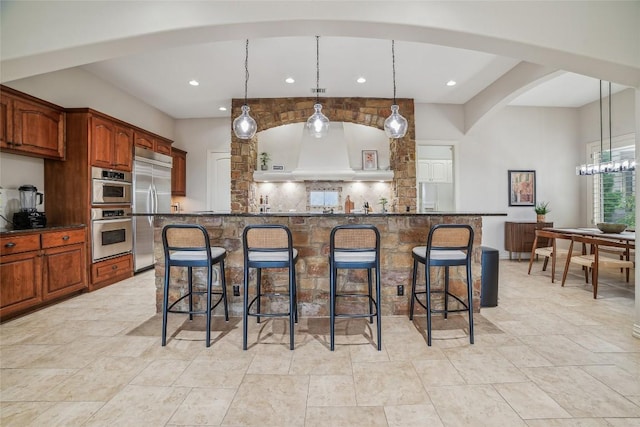 12529 Verandah Ct, Austin, TX 78726 - kitchen with built in fridge, arched walkways, a kitchen breakfast bar, tasteful backsplash, and recessed lighting