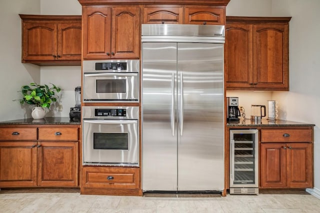 12529 Verandah Ct, Austin, TX 78726 - kitchen featuring stainless steel appliances, beverage cooler, brown cabinetry, and dark stone counters