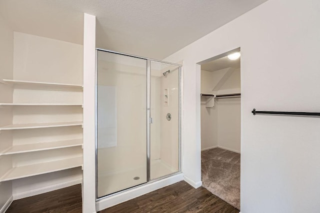 14309 Deaf Smith Blvd, Austin, TX 78725 - bathroom featuring a stall shower, a spacious closet, wood finished floors, and baseboards