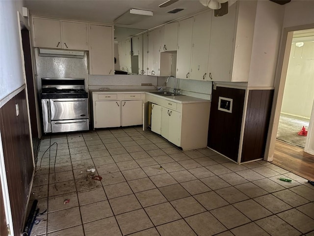 200 W Odell St, Austin, TX 78752 - kitchen featuring stainless steel gas range oven, under cabinet range hood, light tile patterned flooring, light countertops, and white cabinetry