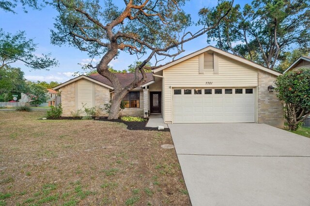 7701 Lowdes Dr, Austin, TX 78745 - mid-century modern home featuring an attached garage, brick siding, driveway, and a front lawn