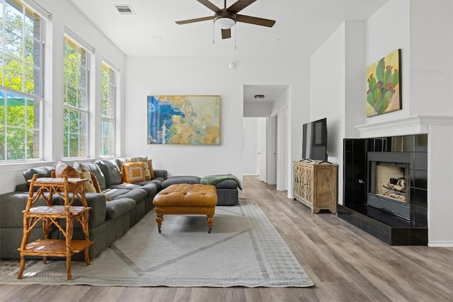 9205 Amanda Dr, Austin, TX 78729 - living room with wood finished floors, a ceiling fan, a tiled fireplace, and a high ceiling