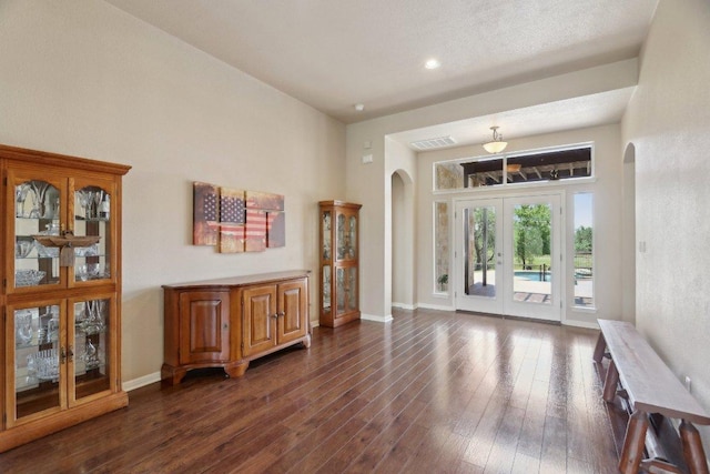 816 Drifting Wind Run, Dripping Springs, TX 78620 - living room featuring arched walkways, dark wood-style flooring, baseboards, a towering ceiling, and french doors