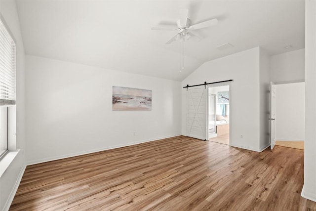 260 Kiras Ct, Austin, TX 78737 - unfurnished bedroom with a barn door, lofted ceiling, wood finished floors, ensuite bath, and a ceiling fan
