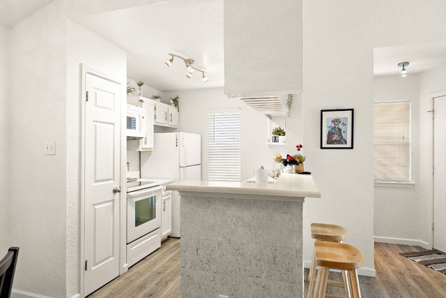 1601 Faro Dr Unit 303, Austin, TX 78741 - kitchen featuring white appliances, light wood finished floors, a kitchen breakfast bar, and a peninsula