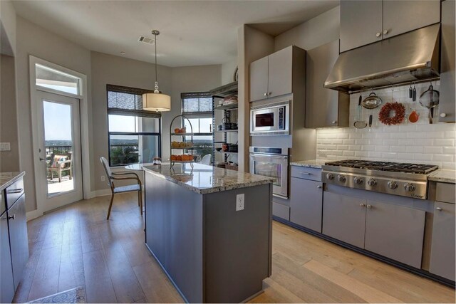 8200 SW Pkwy Unit 721, Austin, TX 78735 - kitchen featuring appliances with stainless steel finishes, under cabinet range hood, tasteful backsplash, and light wood-type flooring