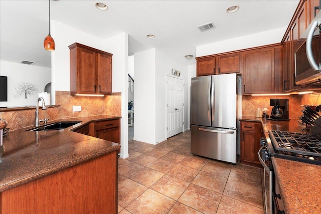 141 Wildcat Draw Dr, Buda, TX 78610 - kitchen featuring appliances with stainless steel finishes, a sink, backsplash, dark stone countertops, and pendant lighting