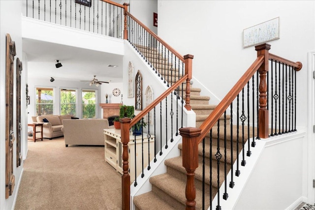 141 Wildcat Draw Dr, Buda, TX 78610 - stairway with a ceiling fan, a fireplace, carpet floors, and a towering ceiling