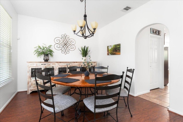 141 Wildcat Draw Dr, Buda, TX 78610 - dining room featuring a chandelier, arched walkways, dark wood-style flooring, and baseboards