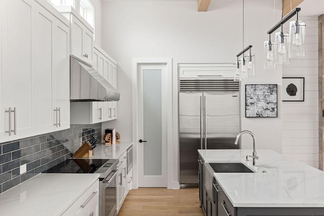13410 Galleria Cir, Austin, TX 78738 - kitchen with built in appliances, light wood-type flooring, extractor fan, backsplash, and white cabinetry