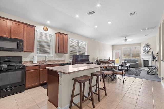 1608 Torre St, Leander, TX 78641 - kitchen with black appliances, open floor plan, a fireplace, light tile patterned floors, and healthy amount of natural light
