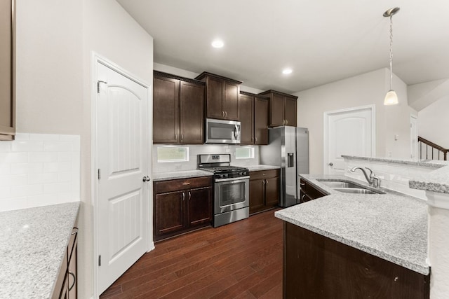 7709 Menchaca Rd Unit 5, Austin, TX 78745 - kitchen featuring appliances with stainless steel finishes, dark wood finished floors, dark brown cabinetry, decorative backsplash, and decorative light fixtures
