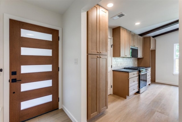 8409 Kimble Cv, Austin, TX 78757 - kitchen with stainless steel range with gas stovetop, light wood-type flooring, tasteful backsplash, baseboards, and dark countertops