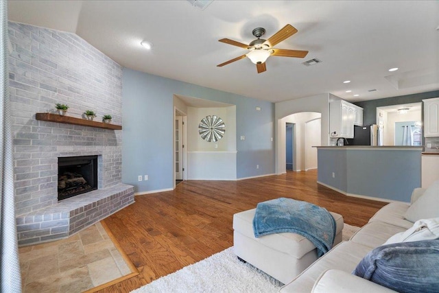 1509 Foster Dr, Cedar Park, TX 78613 - living area with a ceiling fan, arched walkways, a brick fireplace, and wood finished floors