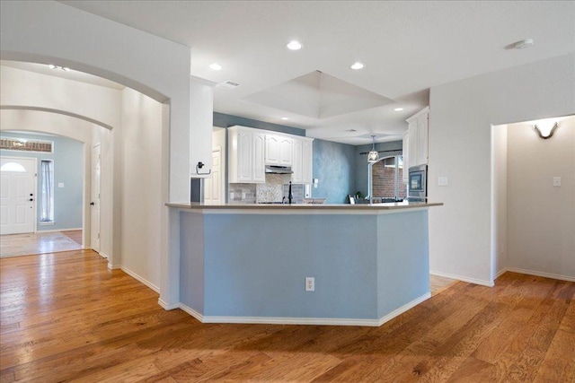 1509 Foster Dr, Cedar Park, TX 78613 - kitchen with stainless steel microwave, a peninsula, light wood-type flooring, white cabinets, and under cabinet range hood