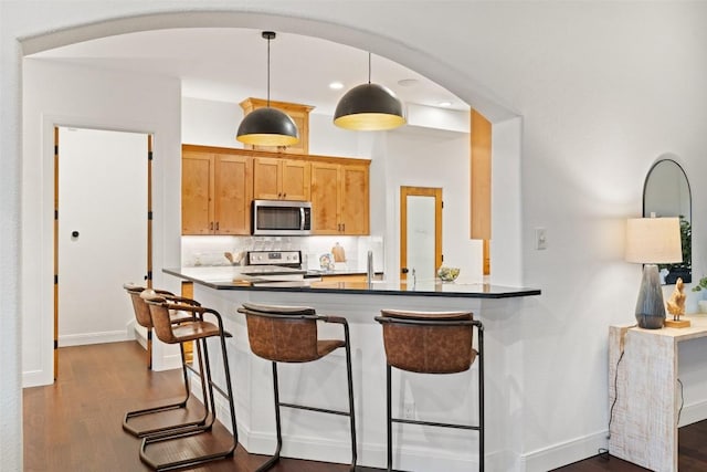 321 Hannah Dr, Dripping Springs, TX 78620 - kitchen with stainless steel microwave, stove, dark wood-style floors, and arched walkways