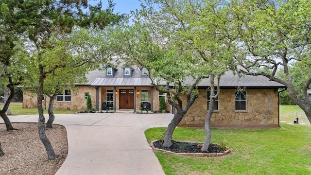 321 Hannah Dr, Dripping Springs, TX 78620 - view of front of property with stone siding, a front yard, curved driveway, a standing seam roof, and roof with shingles