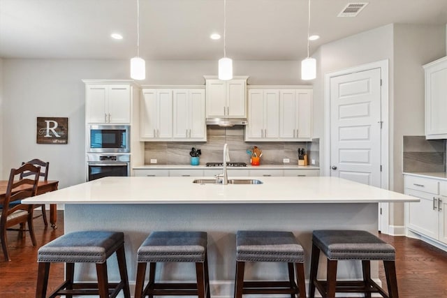 1005 Hezekiah Ln, Leander, TX 78641 - kitchen with stainless steel appliances, under cabinet range hood, decorative backsplash, white cabinetry, and recessed lighting