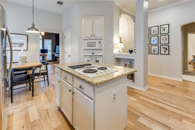 13532 Utah Flats Dr, Austin, TX 78727 - kitchen with arched walkways, white appliances, a kitchen island, light wood-type flooring, and ornamental molding