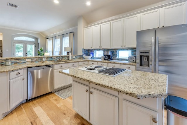 13532 Utah Flats Dr, Austin, TX 78727 - kitchen with stainless steel appliances, a sink, light wood-style flooring, vaulted ceiling, and a peninsula