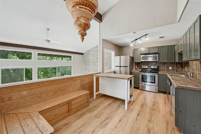 907 The High Rd, Austin, TX 78746 - kitchen with appliances with stainless steel finishes, gray cabinetry, a sink, decorative backsplash, and light wood-style floors