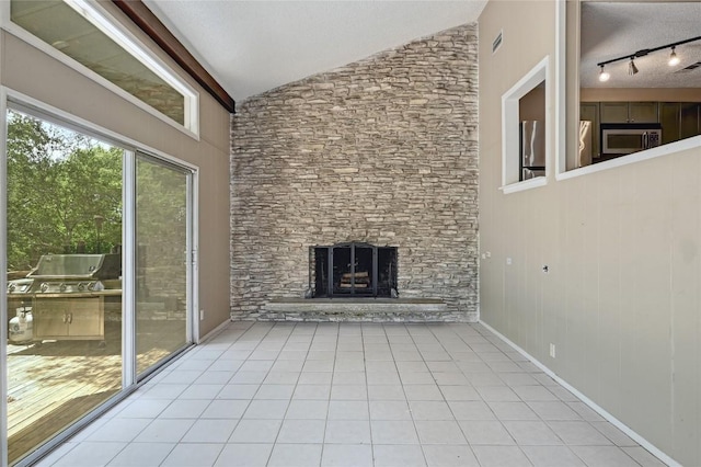 907 The High Rd, Austin, TX 78746 - unfurnished living room featuring vaulted ceiling, a fireplace, light tile patterned floors, and rail lighting