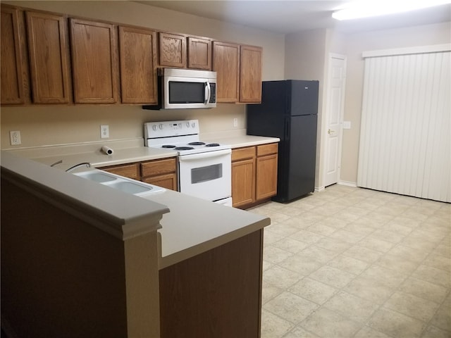 1516 Anise Dr, Austin, TX 78741 - kitchen featuring electric range, stainless steel microwave, freestanding refrigerator, a sink, and brown cabinetry