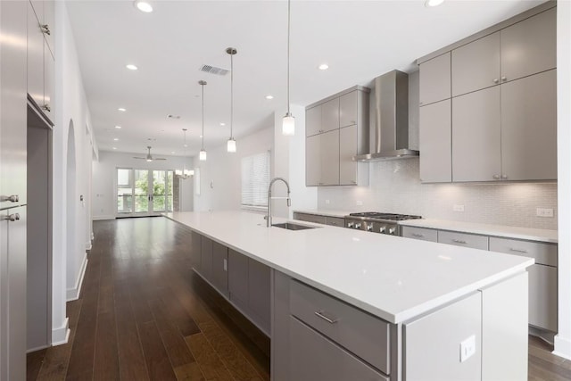 4703 Unity Cir Unit 284, Austin, TX 78731 - kitchen with wall chimney exhaust hood, gray cabinetry, a sink, dark wood finished floors, and tasteful backsplash