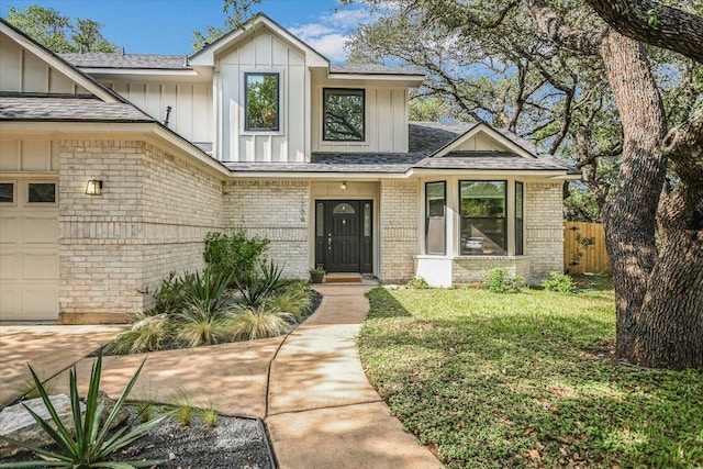 1704 Prairie Hen Cv, Austin, TX 78758 - view of front of property featuring board and batten siding, brick siding, an attached garage, and a shingled roof