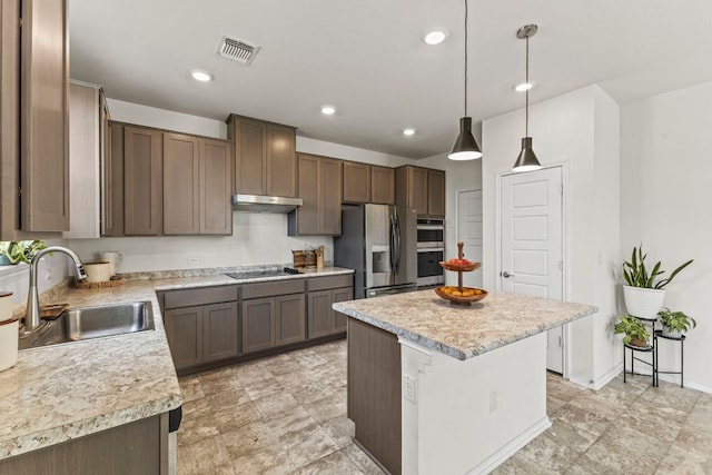18517 Spotted Eagle Ln, Elgin, TX 78621 - kitchen featuring appliances with stainless steel finishes, light countertops, under cabinet range hood, a center island, and pendant lighting