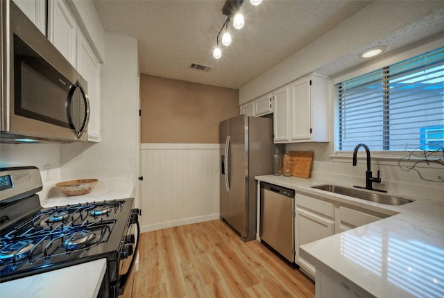 615 Twin Oak Trl, Cedar Park, TX 78613 - kitchen featuring stainless steel appliances, a textured ceiling, white cabinetry, a wainscoted wall, and light countertops