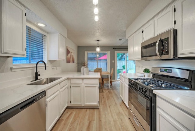 615 Twin Oak Trl, Cedar Park, TX 78613 - kitchen with stainless steel appliances, a textured ceiling, light wood-type flooring, white cabinetry, and a peninsula