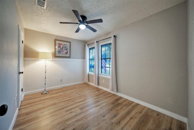 615 Twin Oak Trl, Cedar Park, TX 78613 - spare room with wood finished floors, a ceiling fan, a textured ceiling, and wainscoting