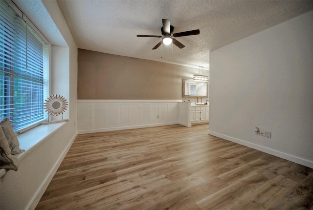 615 Twin Oak Trl, Cedar Park, TX 78613 - unfurnished room featuring a textured ceiling, ceiling fan, light wood-type flooring, and a wainscoted wall